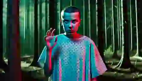 Eleven stands in a dark forest, wearing a hospital gown, her hand raised, concentrating on her telekinetic powers.